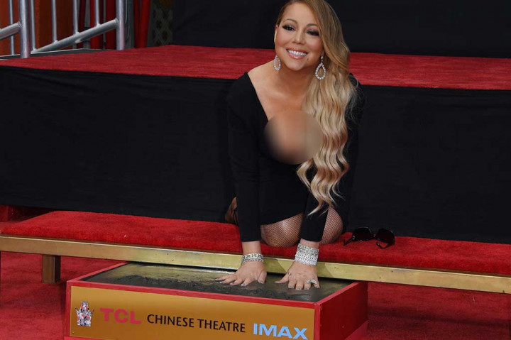 Mariah Carey tanpa canggung mencetak tangannya di semen di TCL Chinese Theatre, Los Angeles. 