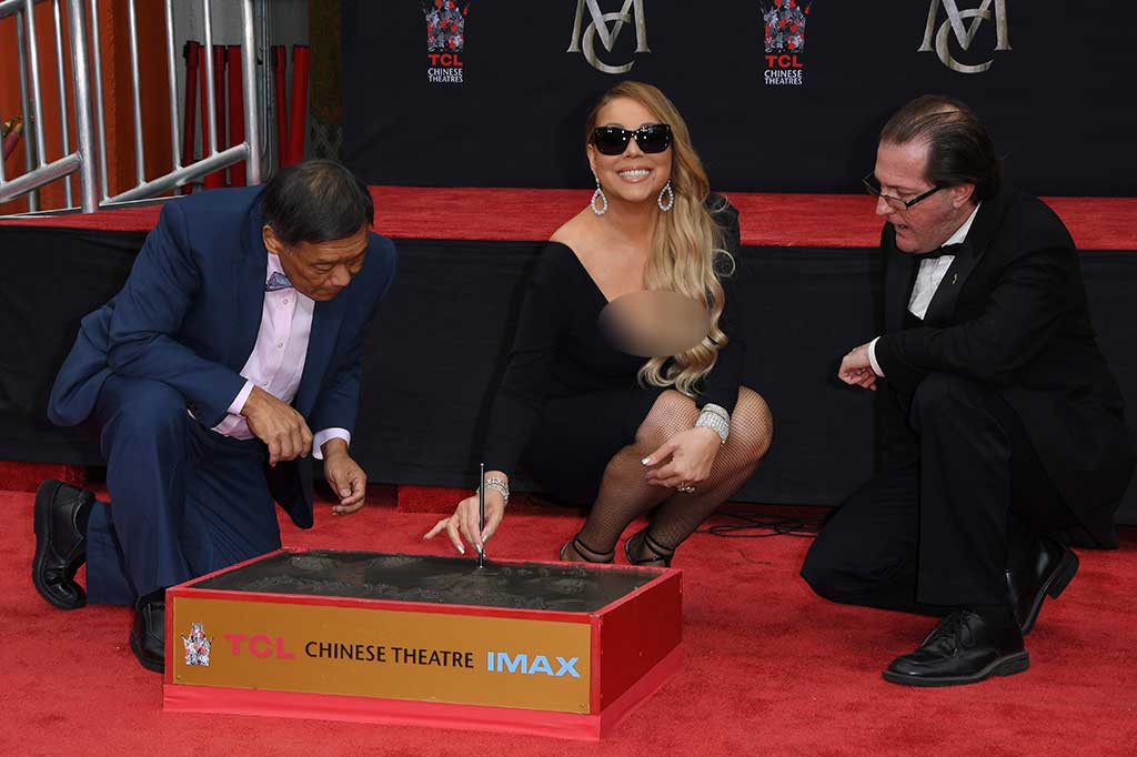 Mengenakan gaun berwarna hitam dengan sepatu berhak tinggi senada, serta kacamata hitam, penyanyi 47 tahun tersebut membubuhkan tanda tangan di atas sekotak semen basah.