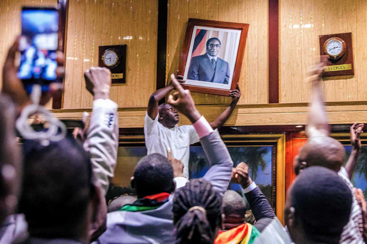 Warga mencopot foto Mugabe yang terpampang di Gedung Parlemen. AFP/Jekesai Njikizana