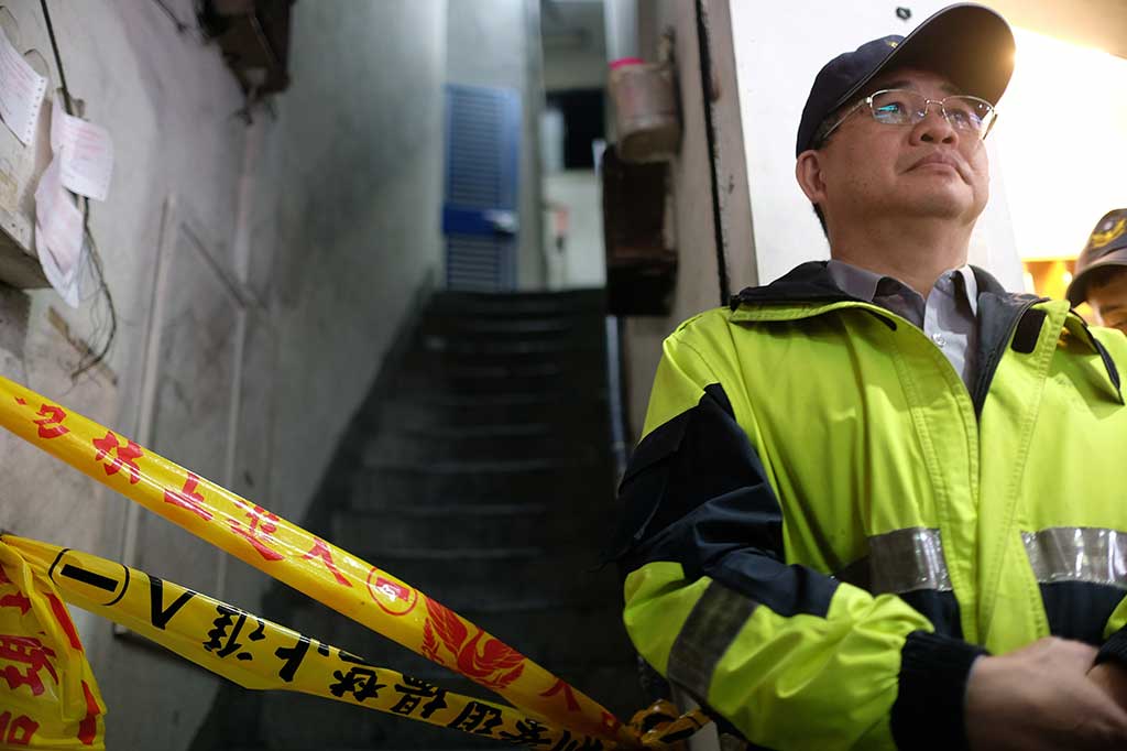 Seorang polisi berjaga-jaga di pintu masuk gedung apartemen empat lantai yang mengalami kebakaran di Distrik Zhonghe, New Taipei, Kamis, 23 November 2017.
