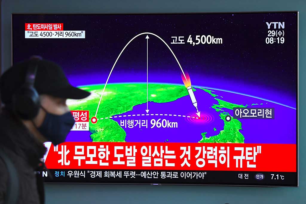 Seorang pria berjalan di dekat televisi di sebuah stasiun KA di Seoul, yang tengah menyiarkan peluncuran rudal balistik oleh Korea Utara. AFP/Jung Yeon-Je