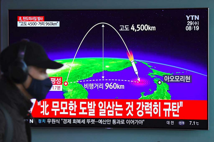 Seorang pria berjalan di dekat televisi di sebuah stasiun KA di Seoul, yang tengah menyiarkan peluncuran rudal balistik oleh Korea Utara. AFP/Jung Yeon-Je