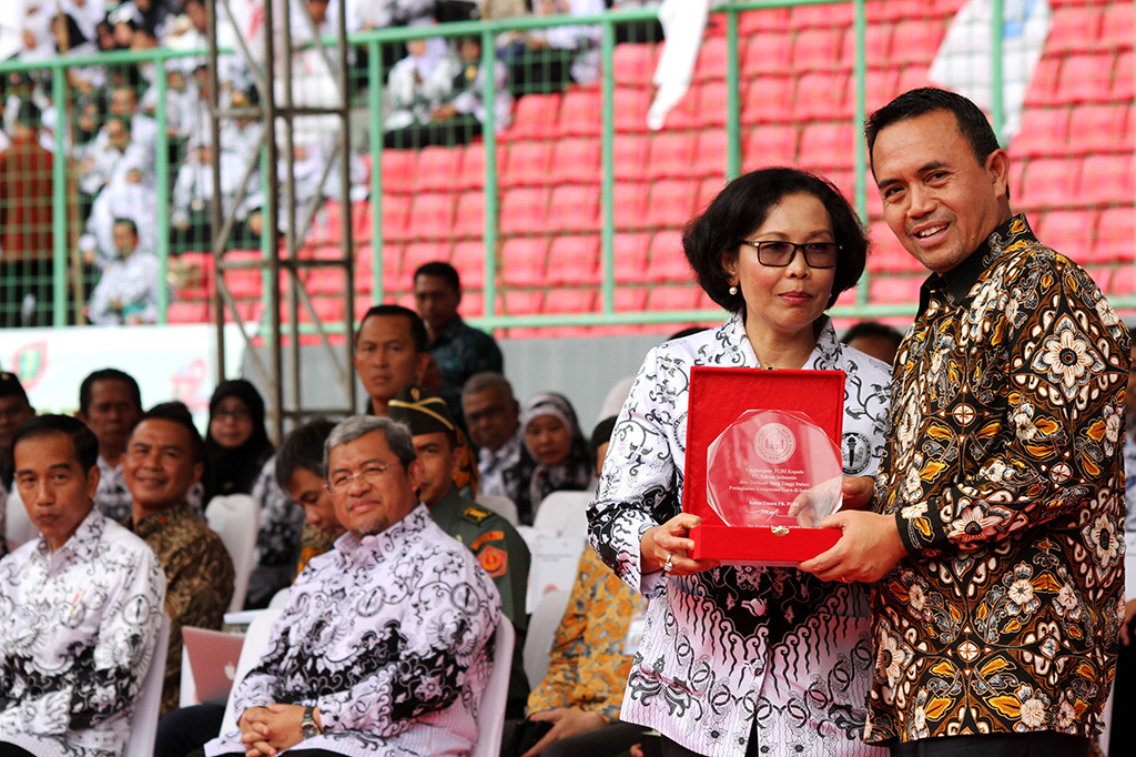 Ketua Umum PGRI Unifah Rosyidi memberikan penghargaan atas dedikasi peningkatan kompetensi guru kepada PT Telkom Indonesia yang diwakili oleh Direktur Human Capital Management PT Telkom Herdy Rosadi Harman disaksikan Presiden Joko Widodo dalam acara puncak peringatan Hari Guru Nasional di Stadion Patriot Candrabhaga, Bekasi, Jawa Barat.
