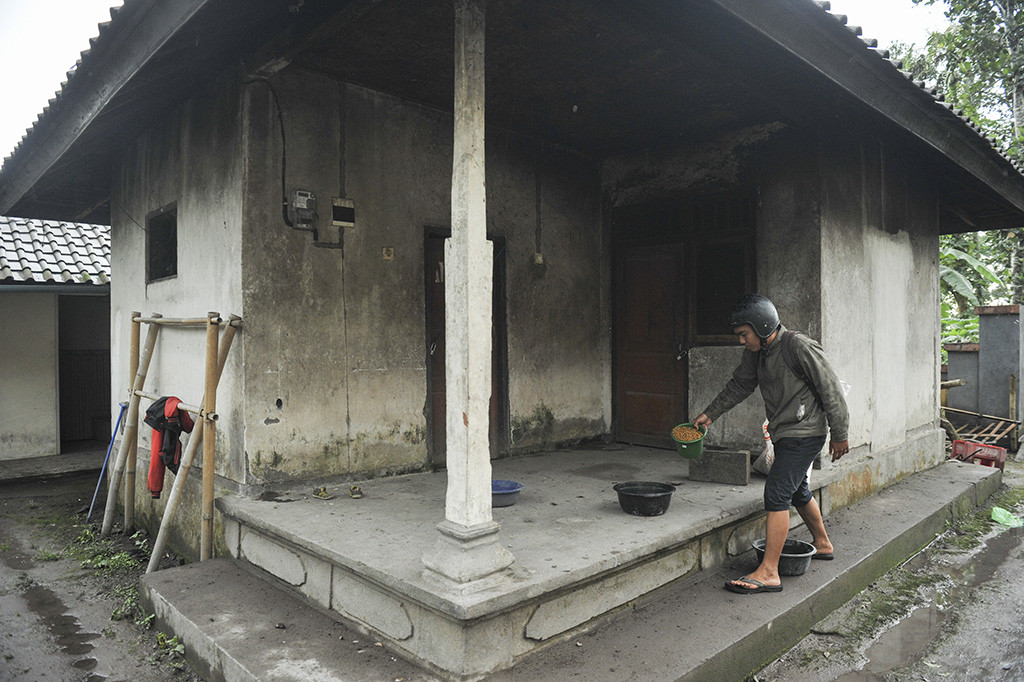 Relawan dari Bali Rumah Singgah Satwa meletakan makanan hewan di sebuah rumah yang ditinggal penghuninya mengungsi, di Sebudi, Karangasem, Bali.