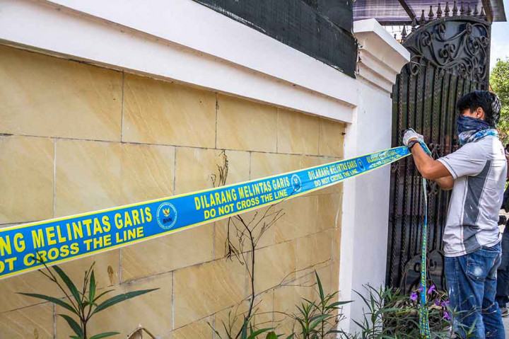 Petugas berpakaian sipil memasang garis larangan melintas di rumah yang diduga menjadi pabrik pembuataan pil PCC di Jalan Raya Halmahera, Semarang. ANTARA/Aji Styawan