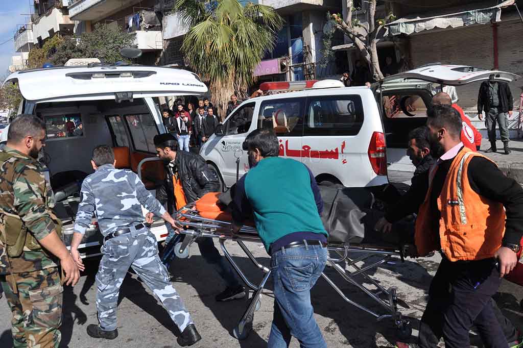 Petugas mengevakuasi korban ledakan bom di Homs, Suriah.