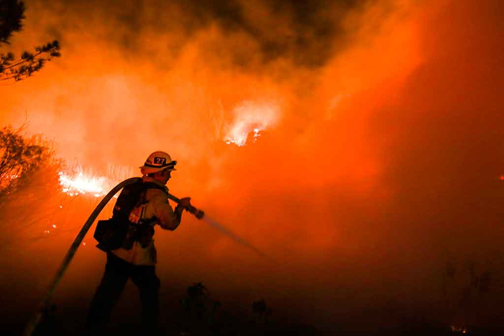 Petugas pemadam kebakaran berusaha keras memadamkan api yang membakar semak-semak dekat permukiman penduduk di Santa Paula, California, Selasa, 5 Desember 2017 waktu setempat.