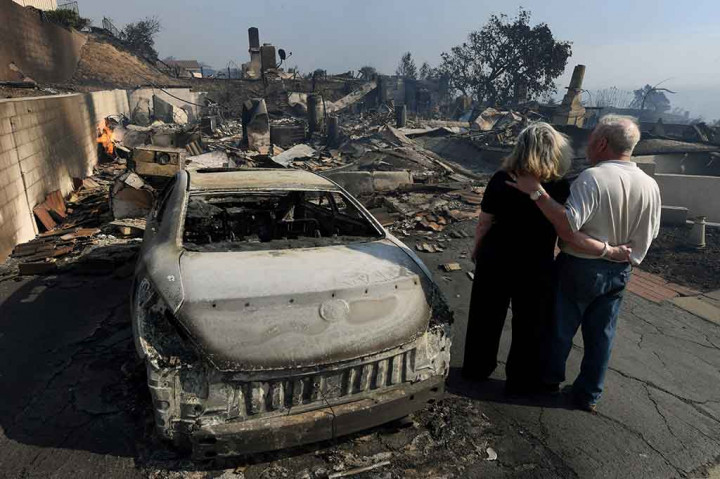 Pasangan suami istri melihat rumah mereka tinggal menyisakan puing-puingnya saja. 