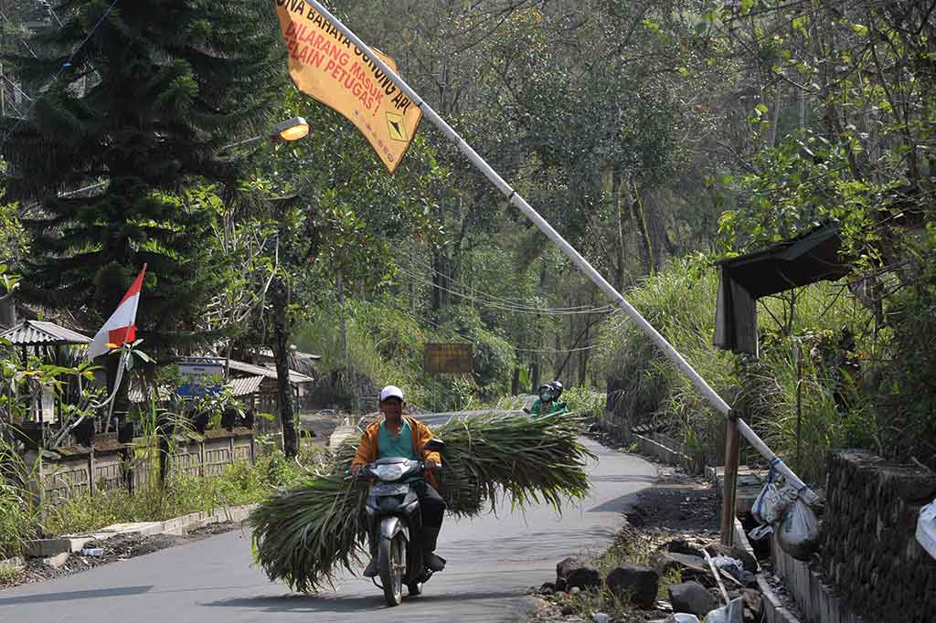 Warga dengan membawa pakan ternak melintasi portal pembatas zona bahaya Gunung Agung di Desa Besakih, Karangasem, Bali, Rabu, 6 Desember 2017.