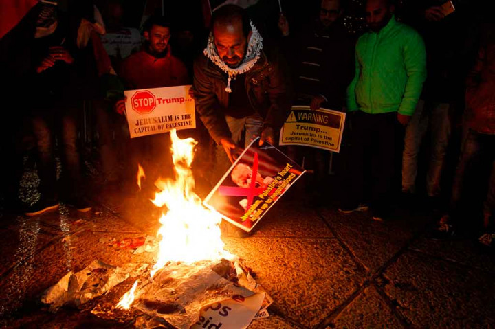 Warga Israel membakar poster Donald Trump di Bethlehem's Manger Square. Pengunjuk rasa mengecam pernyataan Trump yang mengakui Yerusalem sebagai ibu kota Israel dan menginstruksikan pemindahan Kedubes AS dari Tel Aviv ke kota suci tersebut. AFP/Musa Al Shaer