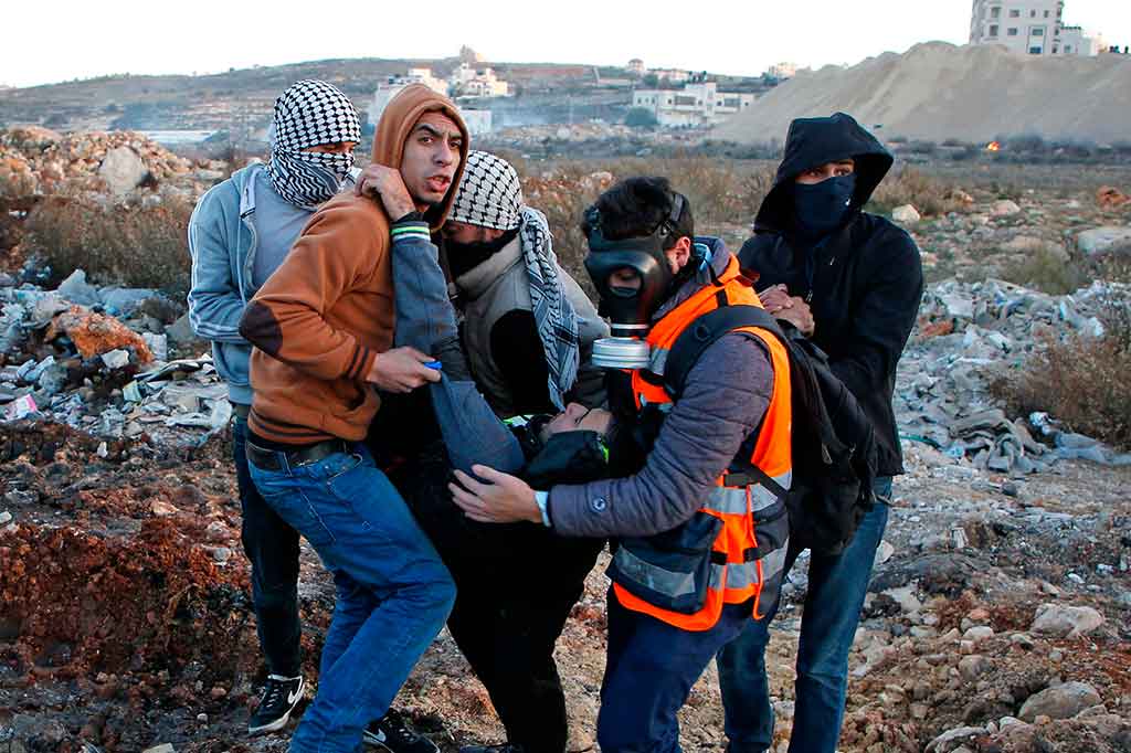 Pemuda Palestina mengevakuasi rekannya yang terluka saat aksi protes di Ramallah, Tepi Barat. AFP/Abbas Momani