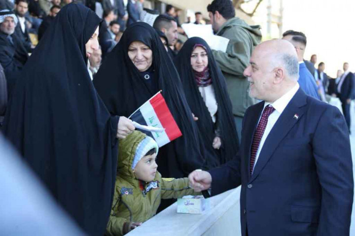 PM Irak menyapa seorang anak di ibu kota Baghdad pada awal sebuah parade militer untuk menandai berakhirnya perang tiga tahun melawan kelompok negara Islam (IS).
