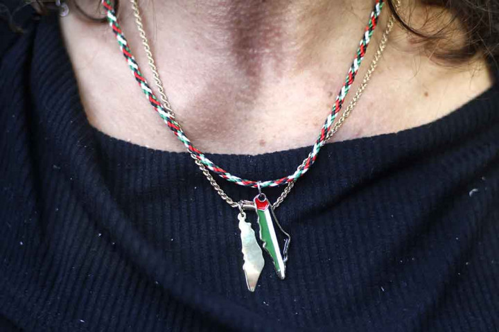 Seorang pengunjuk rasa mengenakan kalung berbentuk peta Palestina dan warna bendera Palestina.