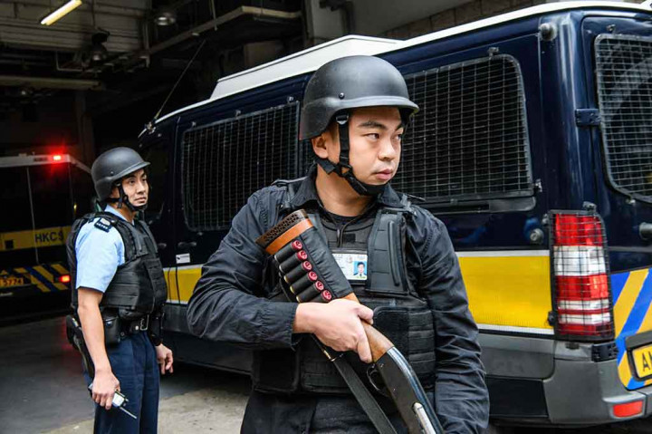 Petugas polisi dengan bersenjata lengkap berjaga di samping bus tahanan yang membawa bankir Inggris Rurik Jutting saat tiba di Pengadilan Tinggi di Hong Kong, Selasa, 12 Desember 2017.