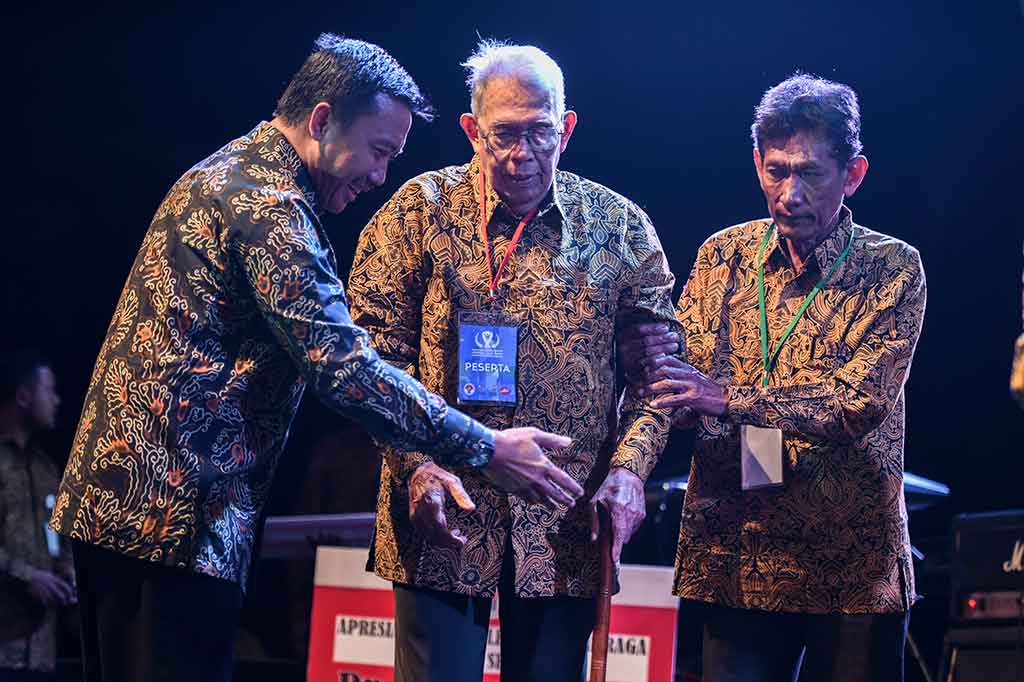 Imam Nahrawi membantu pebalap sepeda legendaris Indonesia Hendra Gunawan (tengah) naik ke atas panggung pada Malam Anugerah Legenda Olahraga Indonesia.