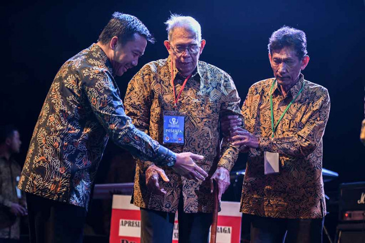 Imam Nahrawi membantu pebalap sepeda legendaris Indonesia Hendra Gunawan (tengah) naik ke atas panggung pada Malam Anugerah Legenda Olahraga Indonesia.
