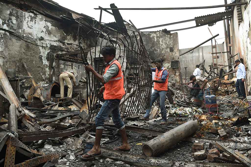 Pekerja membersihkan puing-puing dari lokasi kebakaran sebuah toko di Mumbai, India, Senin, 18 Desember 2017.