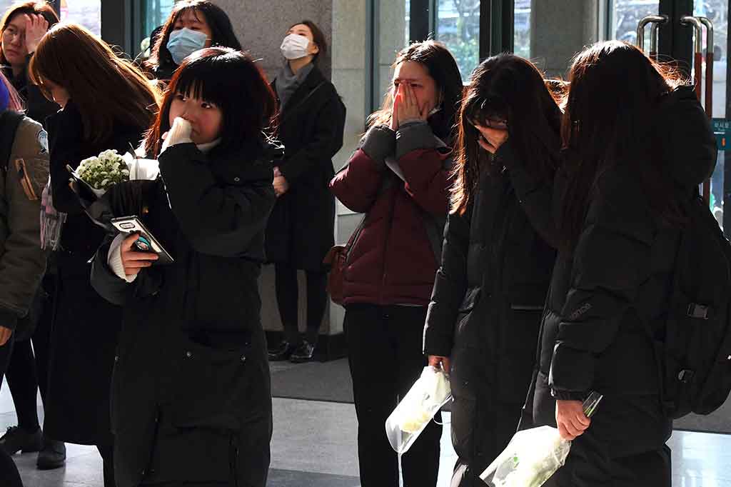 Para penggemar tidak dapat menyembunyikan kesedihannya saat memandangi potret Kim Jong-Hyunm vokalis boyband K-pop SHINee, di papan elektronik di luar rumah duka sebuah rumah sakit di Seoul, Selasa 19 Desember 2017. 