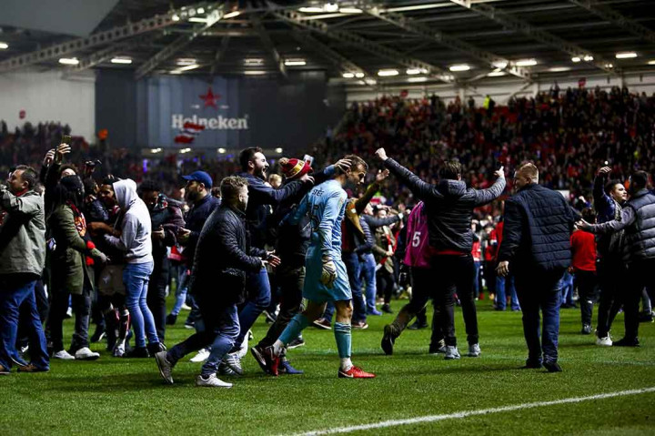 Para penonton tumpah ruah ke dalam lapangan untuk merayakan keberhasilan tim kesayangan mereka melaju ke semifinal Piala Liga Inggris.