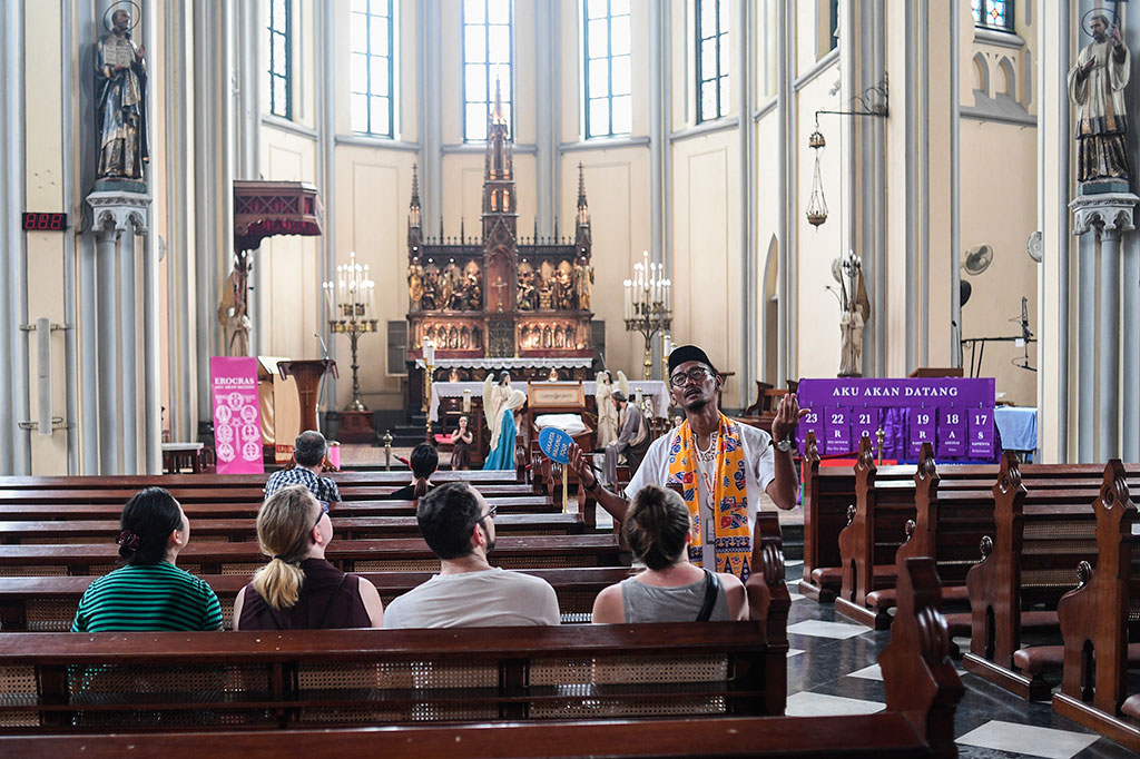 Seorang pemandu wisata menerangkan kepada wisatawan mencanegara yang mengunjungi Gereja Katedral Jakarta.