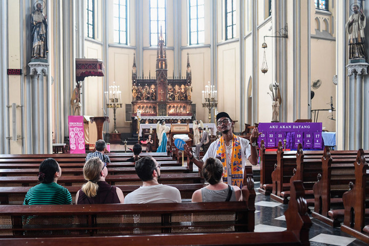 Seorang pemandu wisata menerangkan kepada wisatawan mencanegara yang mengunjungi Gereja Katedral Jakarta.