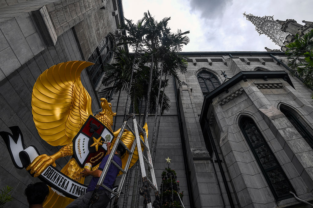 Petugas mengecat lambang Garuda Pancasila sebagai bagian dekorasi jelang perayaan Natal di Gereja Katedral, Jakarta.