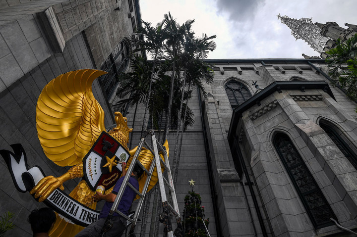 Petugas mengecat lambang Garuda Pancasila sebagai bagian dekorasi jelang perayaan Natal di Gereja Katedral, Jakarta.
