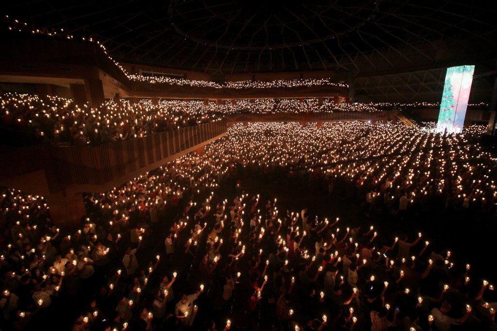 Umat Kristiani menyalakan lilin dalam misa malam Natal di Gereja Bethany, Surabaya, Perayaan Natal 2017 ini mengusung tema 