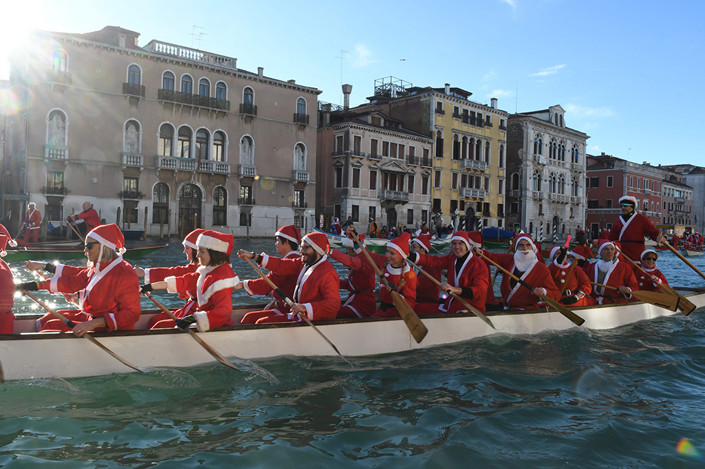Jika di Spanyol para santa mengendari motor gede, di Italia, para Santa di Venesia, Italia, mengendarai perahu kayu. AFP PHOTO / ANDREA PATTARO