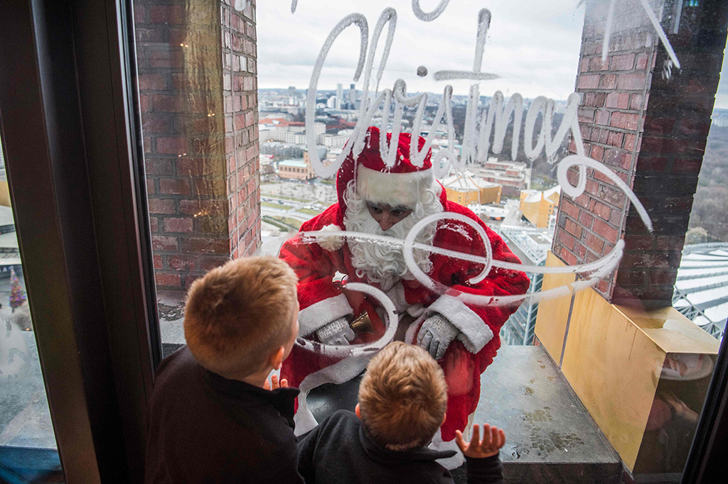 Seorang Santa Claus menghibur anak-anak di puncak menara Kollhoff di Berlin, Jerman. AFP PHOTO / John MACDOUGALL