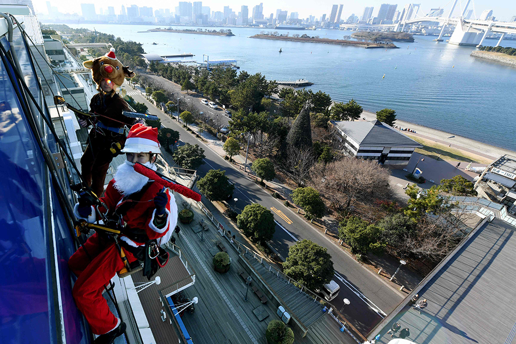 Di Tokyo, Jepang, Santa terlihat membersihkan kaca gedung. AFP PHOTO / Toshifumi KITAMURA