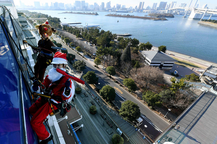 Di Tokyo, Jepang, Santa terlihat membersihkan kaca gedung. AFP PHOTO / Toshifumi KITAMURA
