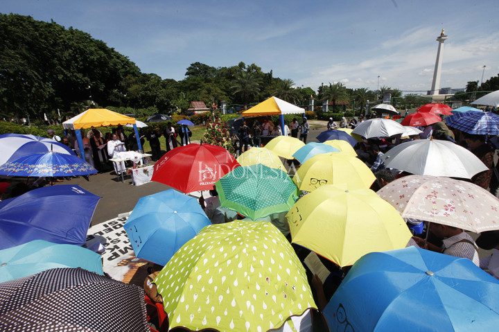Meski di bawah terik matahari, jemaah tampak khidmat mengikuti jalannya Ibadah Natal. Mereka menggunakan payung untuk melindungi diri dari teriknya matahari pada siang ini. 