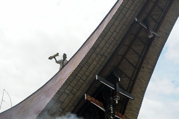 
Seorang pemangku adat mengelilingi atap Tongkonan yang diupacarakan sambil membawa obor saat Upacara Mangrara Banua secara Aluk Todolo di Sangalla, Tana Toraja, Sulawesi Selatan.