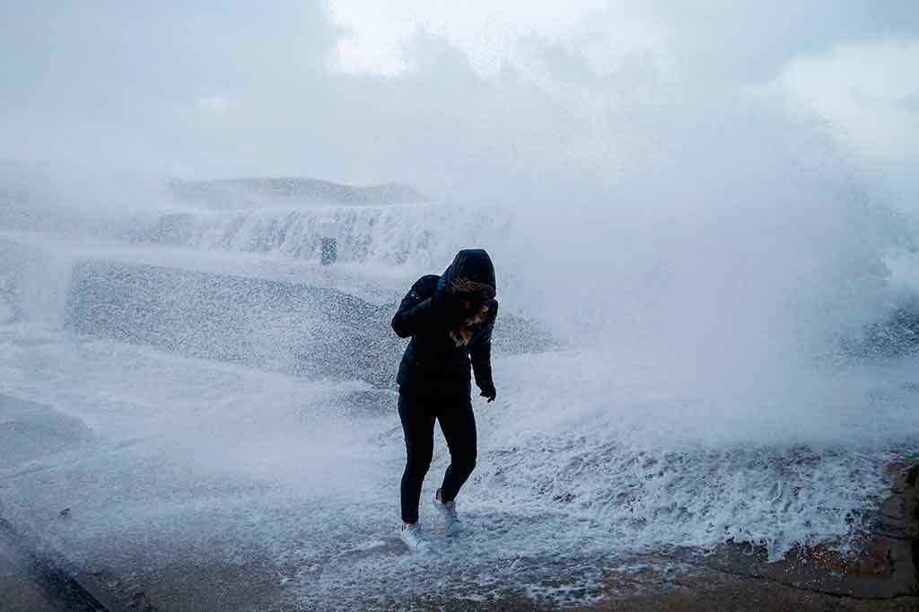 Seorang perempuan berlari mencari perlindungan dari terjangan ombak di pinggir laut di Auderville, Normandia, Prancis, Rabu, 3 Januari 2018 waktu setempat. AFP/Charly Triballeau