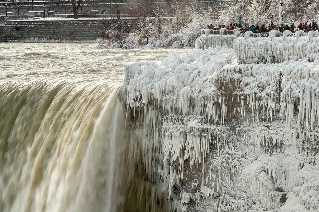 Puluhan wisatawan rela menahan rasa dingin yang menusuk tulang untuk mengabadikan fenomena alam membekunya air terjun Niagara di sisi Kanada, Ontario.