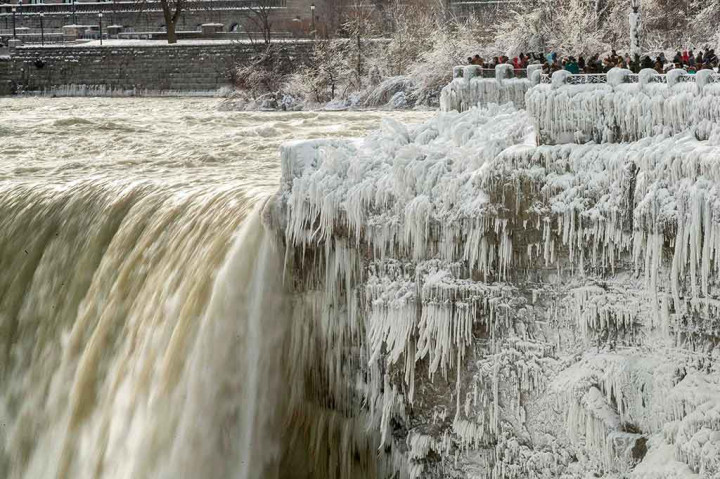 Puluhan wisatawan rela menahan rasa dingin yang menusuk tulang untuk mengabadikan fenomena alam membekunya air terjun Niagara di sisi Kanada, Ontario.