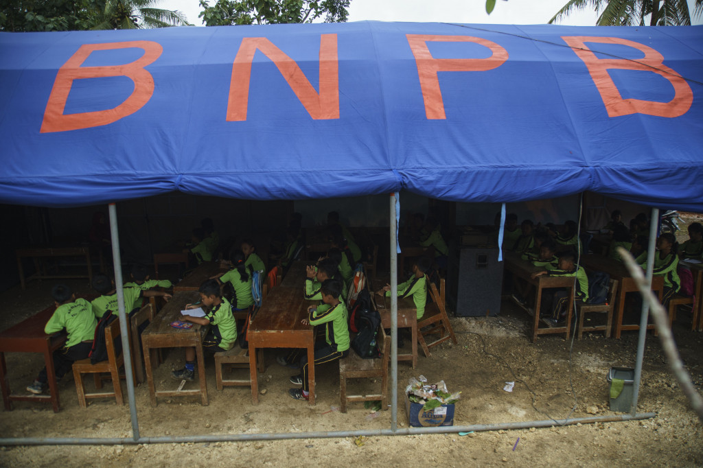 Sejumlah siswa SDN Seropan mengikuti kegiatan belajar mengajar di dalam tenda di halaman TK Aisyiyah, di Desa Muntuk, Dlingo, Bantul, DI Yogyakarta, Sabtu, 6 Januari 2018.
