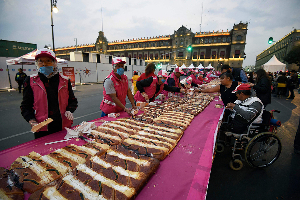 Orang-orang berdiri mengelilingi parade roti Rosca massal di pusat Kota Meksiko. Roti Rosca ini merupakan simbol karangan bunga untuk raja. Bentuk roti ini oval besar yang diisi dengan buah kering atau kismis.