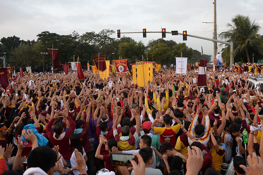 Orang-orang mengangkat tangan dan berdoa saat patung Yesus (Black Nazarene lewat.