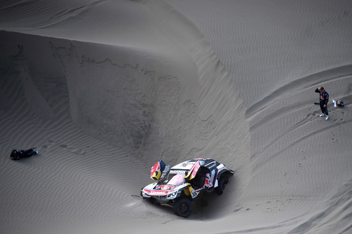 Co-driver Daniel Elena (kiri), dari Monaco, berbaring di pasir setelah mendapat cedera saat dia dan pembalap Prancis Sebastien Loeb mengalami masalah di lubang pasir.