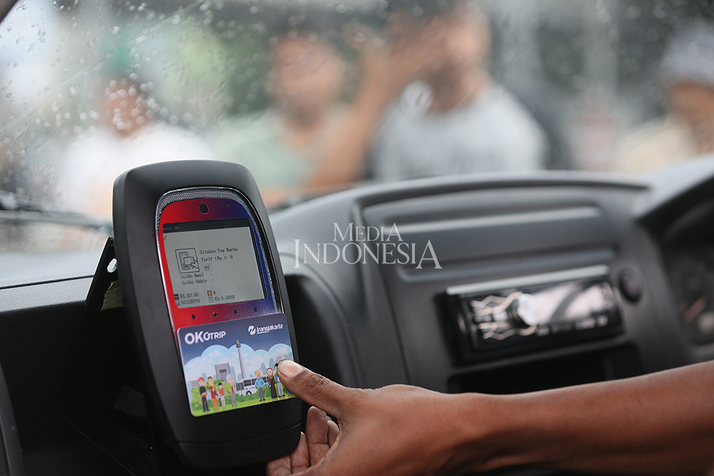 Sopir membantu penumpang melakuka tab menggunakan kartu OK Otrip (One Karcis One Trip) milik penumpang yang menaiki Mikrolet jurusan Kampung Melayu-Duren Sawit di Terminal Kampung Melayu, Jakarta Timur.