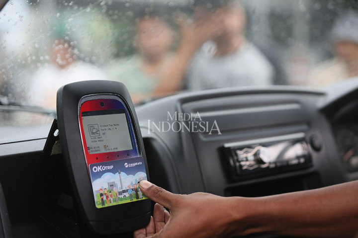 Sopir membantu penumpang melakuka tab menggunakan kartu OK Otrip (One Karcis One Trip) milik penumpang yang menaiki Mikrolet jurusan Kampung Melayu-Duren Sawit di Terminal Kampung Melayu, Jakarta Timur.