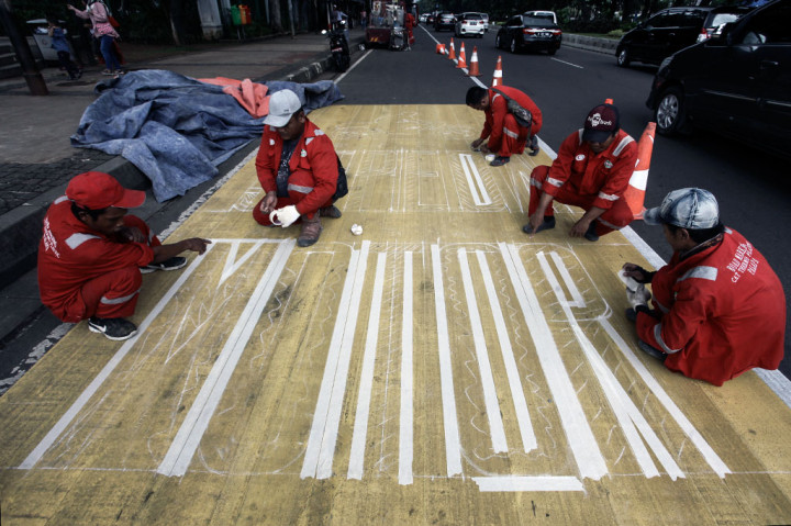 Pekerja mengecat rambu jalur kuning khusus sepeda motor di kawasan Medan Merdeka, Jakarta. ANTARA/Muhammad Adimaja