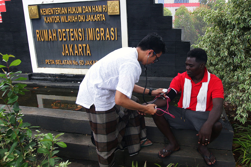 Dokter melakukan pengecekan kesehatan pencari suaka yang tinggal di trotoar.