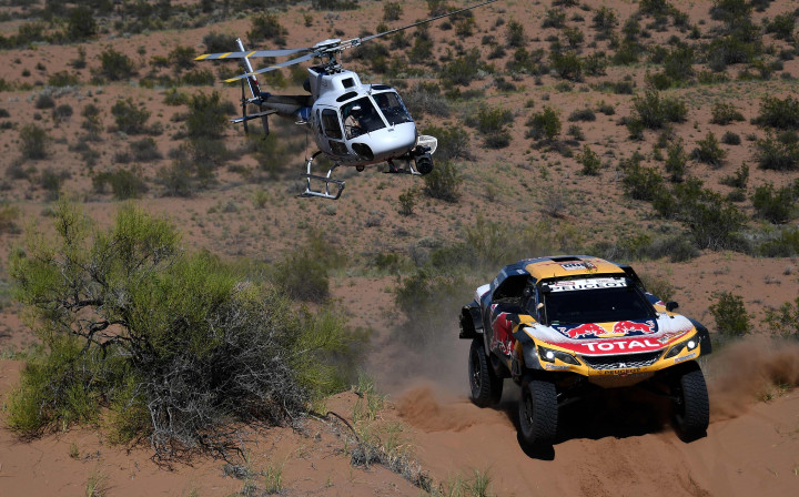 Helikopter panita terbang di atas Peugeot 3008 DKR pacuan Stephane Peterhansel. Mundurnya pereli Sebastien Loeb di etape V merupakan kehilangan besar bagi tim Peugeot.
