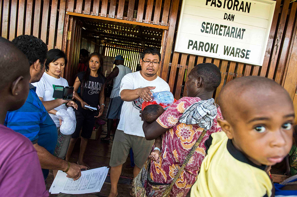 Warga antre pembagian bantuan kemanusian saat KLB campak dan gizi buruk di Distrik Jetsy, Kabupaten Asmat. Bantuan yang dikoordinir oleh tim Keuskupan Agats tersebut akan dibagikan untuk ibu, anak-anak, dan ibu hamil yang mengalami masalah kesehatan di distrik tersebut. 