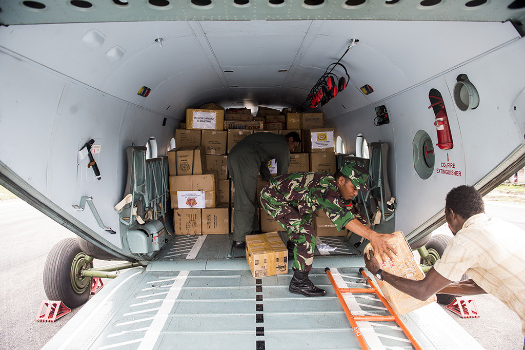 Prajurit TNI bersama warga melakukan bongkar muat bantuan makanan dan obat-obatan di Ewer, Kabupaten Asmat, Papua.