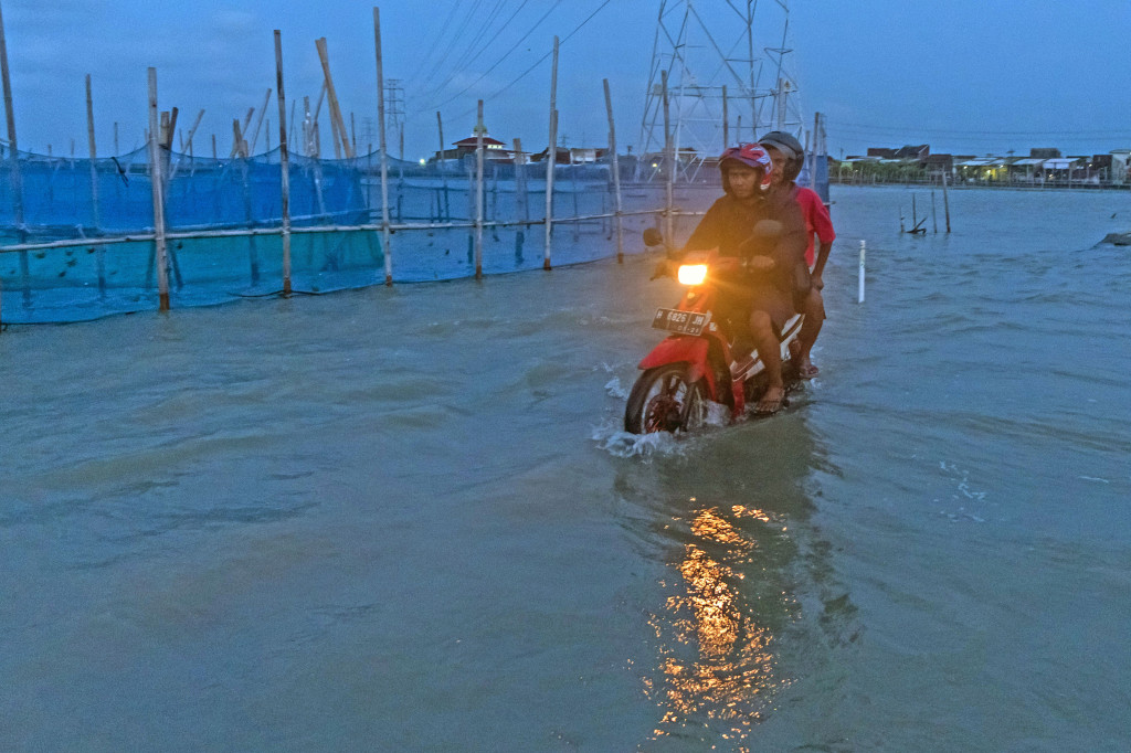 Warga beraktivitas di jalan tegenang air rob di pesisir Desa Sriwulan, Sayung, Demak, Jawa Tengah, Rabu (31/1/3018). Badan Meteorologi Klimatologi dan Geofisika (BMKG) memperkirakan ketinggian air laut pasang di sejumlah wilayah naik antara 1 hingga 1,5 meter sampai surutnya pada Kamis (1/2/2018) pagi.  Antara Foto/Aji Setyawan