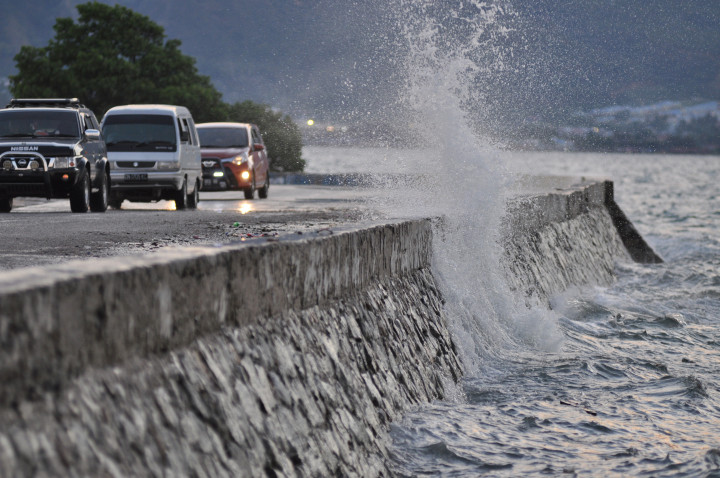 Pengendara melintasi jalan yang diterpa ombak air laut di Pantai Teluk Palu, Sulawesi Tengah, Rabu (31/1/2018). Badan Meteorologi Klimatologi dan Geofisika (BMKG) menghimbau masyarakat yang berada di pesisir pantai agar mewaspadai peningkatan air pasang yang dipicu fenomena alam super blue blood moon dan diperkirakan akan berlangsung hingga 1 Februari 2018. ANTARA FOTO/Mohamad Hamzah